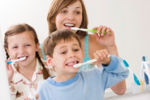 Childrens brushing teeth with mother