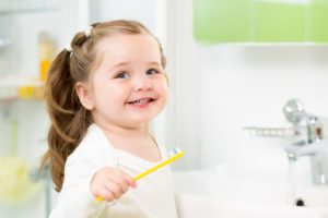 Small girl holding tooth brush and smiling